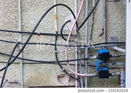 Old water supply pipes with valves and meters mounted on exterior wall of residential building. Urban infrastructure and water distribution system concept 138162829