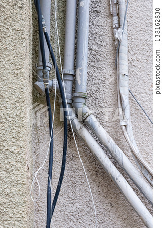 Old water supply pipes with valves and meters mounted on exterior wall of residential building. Urban infrastructure and water distribution system concept 138162830