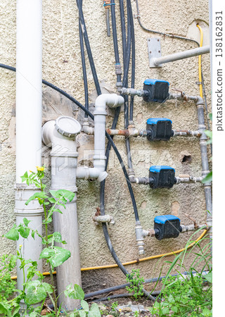 Old water supply pipes with valves and meters mounted on exterior wall of residential building. Urban infrastructure and water distribution system concept 138162831