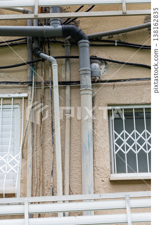 Old water supply pipes with valves and meters mounted on exterior wall of residential building. Urban infrastructure and water distribution system concept 138162835