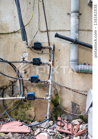 Old water supply pipes with valves and meters mounted on exterior wall of residential building. Urban infrastructure and water distribution system concept 138162838