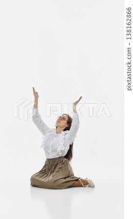 Woman kneeling with raised hands looking up isolated on white background. 138162866