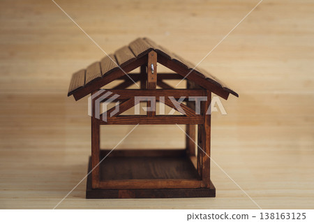 Horizontal three-quarter view of a handcrafted dark wood bird feeder or decorative miniature house, featuring a gabled roof and open timber-frame construction. Horizontal three-quarter view of a handcrafted dark wood bird feeder or decorative miniature house, featuring a gabled roof and open timber-frame construction. 138163125