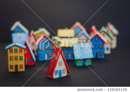 Horizontal view of a colorful collection of handcrafted miniature wooden houses, each uniquely painted with vibrant colors and snowy roofs, arranged on a dark surface. Horizontal view of a colorful collection of handcrafted miniature wooden houses, each uniquely painted with vibrant colors and snowy roofs, arranged on a dark surface. 138163130