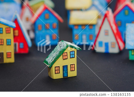 Horizontal view of a colorful collection of handcrafted miniature wooden houses, each uniquely painted with vibrant colors and snowy roofs, arranged on a dark surface. Horizontal view of a colorful collection of handcrafted miniature wooden houses, each uniquely painted with vibrant colors and snowy roofs, arranged on a dark surface. 138163135