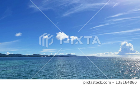 A summer coastal scene with a blue sky and emerald green sea. 138164860
