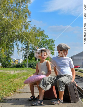 Adorable little girl and boy on a railway station, waiting for the train with vintage suitcase. Traveling, holiday and chilhood concept. Travel insurance concept. Travel, tourism, summer vacation and Adorable little girl and boy on a railway station, waiting for the train with vintage suitcase. Traveling, holiday and chilhood concept. Travel insurance concept. Travel, tourism, summer vacation and 138165505