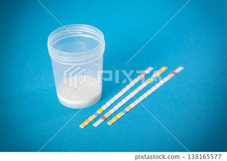 Test strips next to ejaculate analysis on a blue background, concept of measuring leukocytes and microscopy of ejaculate and prostate juice using the express method, close-up Test strips next to ejaculate analysis on a blue background, concept of measuring leukocytes and microscopy of ejaculate and prostate juice using the express method, close-up 138165577