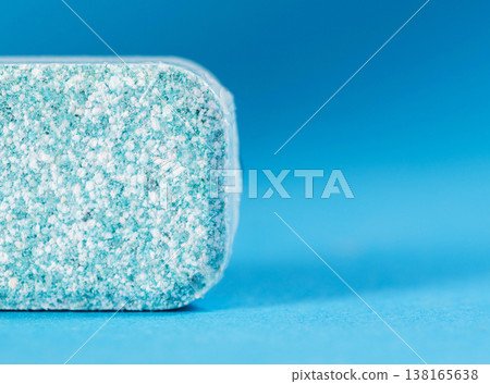 Macro view of dishwasher tablet surface revealing granular blue and white composition of cleaning agent inside transparent plastic packaging. Copy space for text 138165638