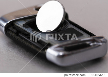 Close-up view of open car key fob showing button battery for replacement procedure detail. Remote control device with electronic circuit exposed on light surface. Close-up view of open car key fob showing button battery for replacement procedure detail. Remote control device with electronic circuit exposed on light surface. 138165648