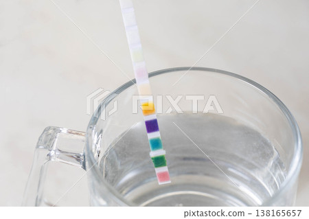 Chemical test strip immersed in clear glass of water for measurement of water parameters composition and quality checking, close up of laboratory analysis equipment for liquid substance purity 138165657