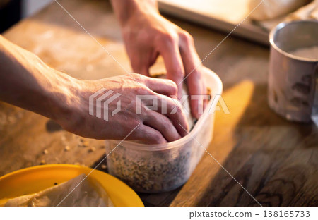 Hands of person carefully placing ingredients into plastic container on wooden table for food preparation activity culinary art healthy eating kitchen environment cooking process homemade snack Hands of person carefully placing ingredients into plastic container on wooden table for food preparation activity culinary art healthy eating kitchen environment cooking process homemade snack 138165733