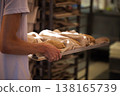Baker hands holding metal baking tray with raw bread dough loaves covered in linen cloth, preparation for baking in artisan bakery workshop 138165739