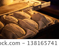 Unbaked bread dough loaves arranged in fabric-lined proofing baskets ready for oven baking in a traditional bread making factory setting 138165741