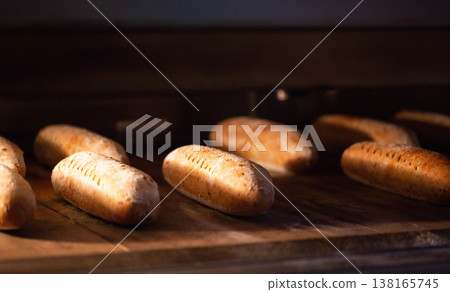 Golden brown artisanal bread loaves baking inside warm dark oven. Freshly baked rustic bread dough cooking to perfection, creating delicious bakery product. Golden brown artisanal bread loaves baking inside warm dark oven. Freshly baked rustic bread dough cooking to perfection, creating delicious bakery product. 138165745