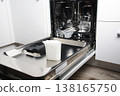 Dishwasher salt in measuring cup inside open dishwasher, ready for pouring into appliance compartment, kitchen maintenance household chore 138165750