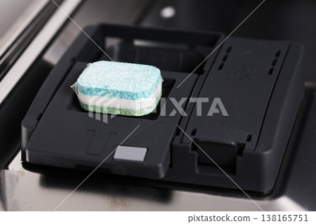 Close up view of multi color dishwasher tablet detergent placed in open dispenser of modern automatic kitchen appliance ready for cleaning cycle of dishes and cutlery 138165751