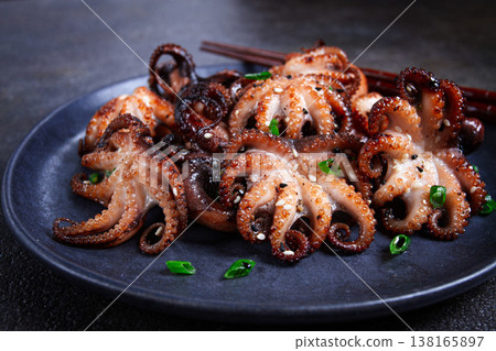 Grilled baby octopus, served with chopsticks, on a black plate, homemade, no people, 138165897