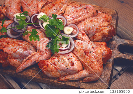 Chicken wings, marinated and laid out on a wooden platter, ready for cooking, grilling or baking, in a home kitchen, there are no people Chicken wings, marinated and laid out on a wooden platter, ready for cooking, grilling or baking, in a home kitchen, there are no people 138165900