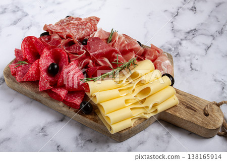 Assorted meat, appetizer, prosciutto, salami and ham, with maasdam cheese and olives, on a wooden board, breakfast, top view, close-up, no people 138165914
