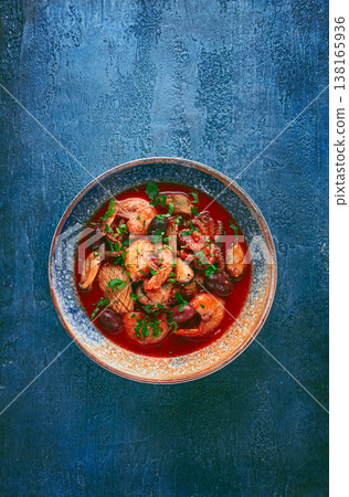 seafood in tomato sauce with olives, on a dark blue background, seafood in tomato sauce with olives, on a dark blue background, 138165936