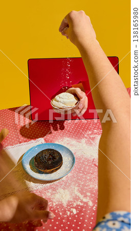 Hand sprinkling flour onto tart emerging from tablet screen on kitchen table Hand sprinkling flour onto tart emerging from tablet screen on kitchen table 138165980
