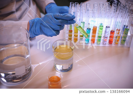 Scientist conducts colorful experiments using test tubes in a modern laboratory setting with vibrant chemical reactions 138166094