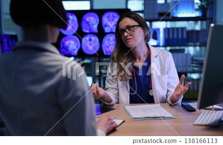 Doctor explains brain scan results to patient in a modern medical office during evening hours Doctor explains brain scan results to patient in a modern medical office during evening hours 138166113