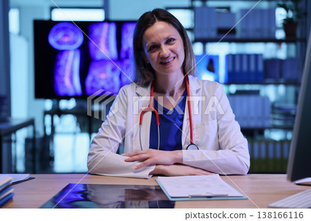 Smiling medical professional in her office reviews patient scans during a calm afternoon Smiling medical professional in her office reviews patient scans during a calm afternoon 138166116