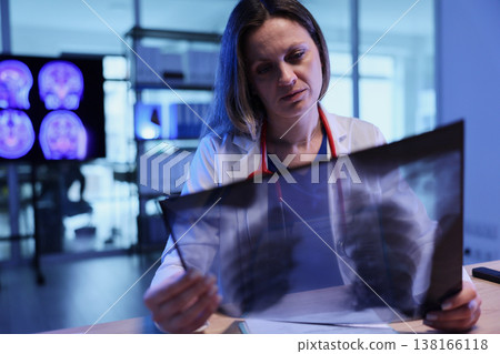 Medical professional examines chest X-ray in a modern clinic during evening hours while pondering health concerns 138166118