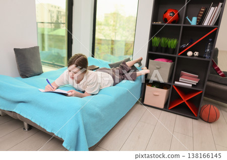 Young girl enjoys writing and creativity in a cozy, modern living room with natural light and vibrant decor 138166145