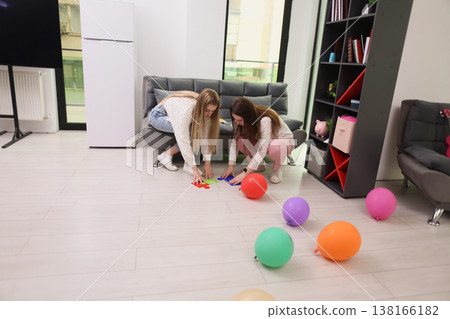 Two friends play a colorful game with balloons on a bright floor in a cozy living room Two friends play a colorful game with balloons on a bright floor in a cozy living room 138166182