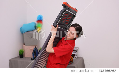 Vacuuming the living room while balancing cleaning tools in a bright, cheerful home setting 138166262