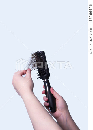Close up woman holding brush after brushing her hair and have many hair loss on the comb Close up woman holding brush after brushing her hair and have many hair loss on the comb 138166466