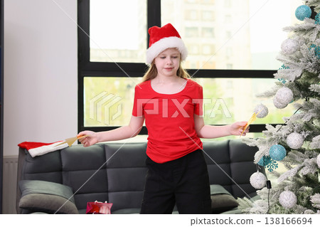 Joyful girl in festive attire decorating Christmas tree with cheerful spirit in cozy living room during holiday season Joyful girl in festive attire decorating Christmas tree with cheerful spirit in cozy living room during holiday season 138166694