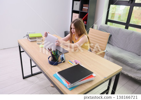 Focused student organizing papers and supplies in a bright, modern study space during a productive afternoon Focused student organizing papers and supplies in a bright, modern study space during a productive afternoon 138166721