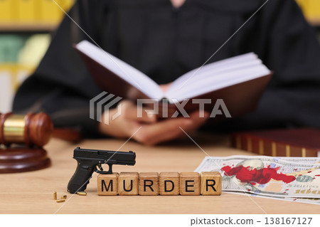Dramatic courtroom scene with a judge reading while gun and murder blocks lie on the table Dramatic courtroom scene with a judge reading while gun and murder blocks lie on the table 138167127