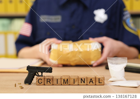 Law enforcement officer examines suspicious package with evidence of crime and illegal substances displayed on the table in bright office setting 138167128