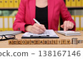 Businesswoman emphasizing responsibility while working at a desk with financial documents and wooden blocks during a productive afternoon 138167146