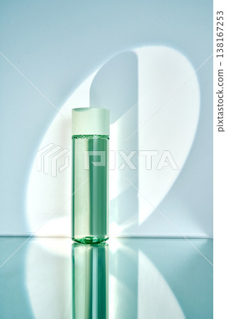 Cosmetic bottle on reflective surface with light shadow 138167253