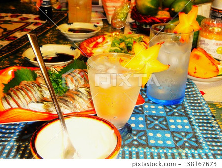 一杯以楊桃裝飾的雞尾酒和一張擺放著生魚片的桌子。 138167673