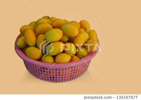 fresh yellow and green Marian Plums placed in a pink plastic basket on yellow background, fruit, food, health, copy space 138167877