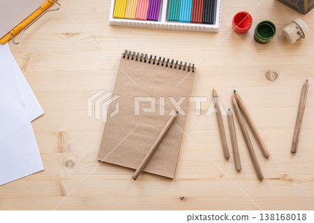 Creative workspace with notebook pencils and art supplies on wooden desk Creative workspace with notebook pencils and art supplies on wooden desk 138168018
