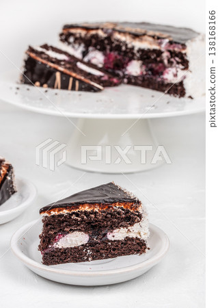 Chocolate cake slice on plate with whole cake on stand background Chocolate cake slice on plate with whole cake on stand background 138168166