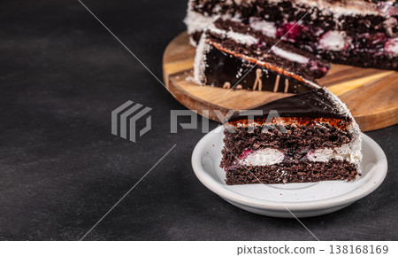 Chocolate cake slice on plate with whole cake on wooden board Chocolate cake slice on plate with whole cake on wooden board 138168169