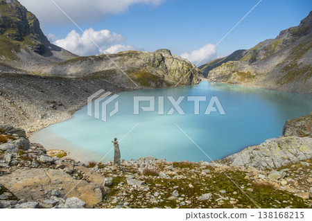 Captivating landscape of Pizol Wildsee lake in the Swiss Alps, featuring tranquil turquoise water amid rugged peaks enveloped by mist and clouds, creating a dramatic mountain scene Captivating landscape of Pizol Wildsee lake in the Swiss Alps, featuring tranquil turquoise water amid rugged peaks enveloped by mist and clouds, creating a dramatic mountain scene 138168215