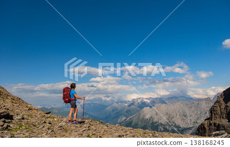 A lone hiker pauses on a rocky peak, gazing at the breathtaking mountainous terrain below. Sporty woman hiking in Switzerland alps. Heathy lifestyle, sport, beauty in nature. Grindelwald valley, Swizz A lone hiker pauses on a rocky peak, gazing at the breathtaking mountainous terrain below. Sporty woman hiking in Switzerland alps. Heathy lifestyle, sport, beauty in nature. Grindelwald valley, Swizz 138168245