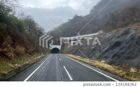 A rural mountain road and tunnel entrance: A cloudy driving scene. A rural mountain road and tunnel entrance: A cloudy driving scene. 138168362