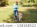 Owner woman walking with her Golden Retriever dog on leash in summer park 138168522