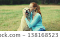 Happy owner woman with Golden Retriever dog sitting on grass together in park 138168523